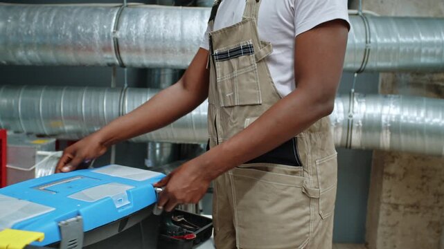 Man opens tool box for work on building site with tools and equipment