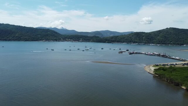 Drone shot emerging from the Rio Pereque Acu, capturing Baia de Paraty, surrounding islands, mountains, and the Atlantic forest and boats anchored in the bay, showcasing the regions coastal beauty