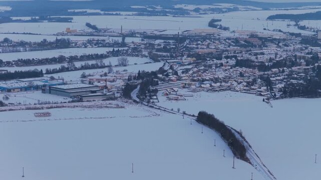 The town in the early evening from an aerial view during a cold winter. A train entering the town. The snow-covered Czech town of Svitavy.