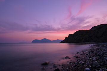 Purple Sunset Over Calm Seaside Cliffs and Pebble Beach at Dusk, Quiet Ocean Landscape