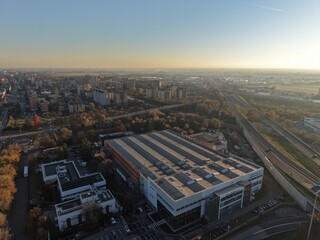An expansive aerial perspective of a modern cityscape, showcasing a blend of urban development and natural elements under a clear, bright sky. 