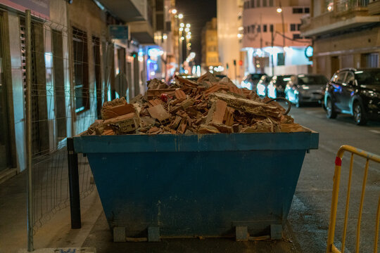 Construction waste dumpster on city street at night