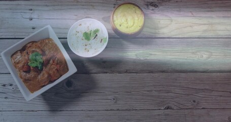 Showing white square bowl with brown curry and cilantro on weathered table, rice, dal, copy space © vectorfusionart