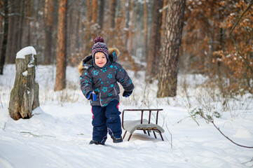 joyful child enjoying sledding in winter forest. Natural lifestyle moments of childhood fun, outdoor play, and seasonal recreation in cold weather