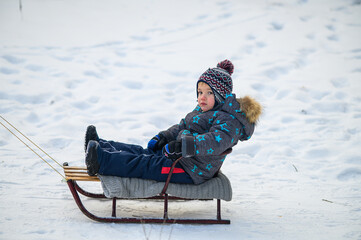 joyful child enjoying sledding in winter forest. Natural lifestyle moments of childhood fun, outdoor play, and seasonal recreation in cold weather