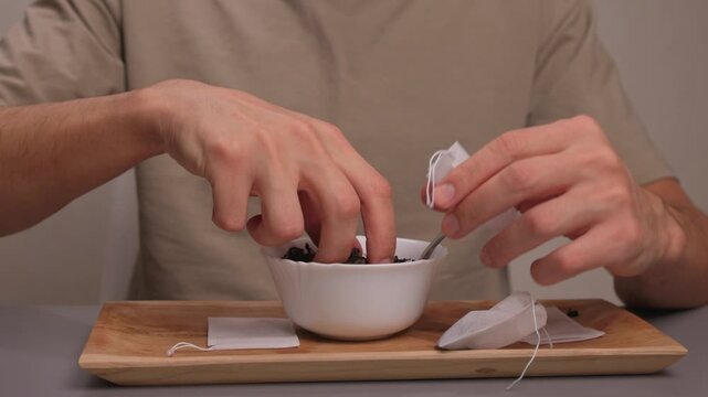 Artisan tea bag filling process, Careful and detailed artisanal approach to tea packaging, Meticulous handpicked tea bags with loose leaves and scattered empty sachets on tray