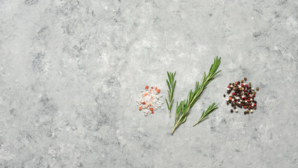 Rosemary, salt, and peppercorns on a gray grunge background. Top view, flat lay, copy space. Culinary background with spices.