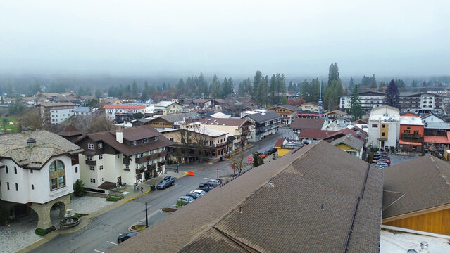 Front Street corridor near the Wenatchee River shows clustered Bavarian facades and steady visitor movement along the main block. Timber accents, steep roofs settle under fog in Leavenworth, WA