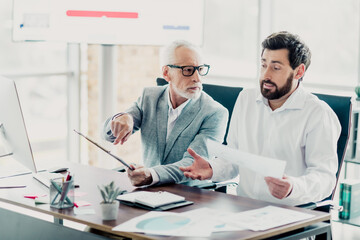 Obraz premium Business meeting between two colleagues in a modern loft office discussing documents and charts