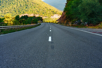 Obraz premium Winding road through green hills at sunset in a mountain area