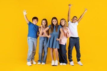 Obraz premium Confident group of preteen kids posing together on yellow studio background. Concept of teamwork, leadership, diversity, education, and positive childhood development