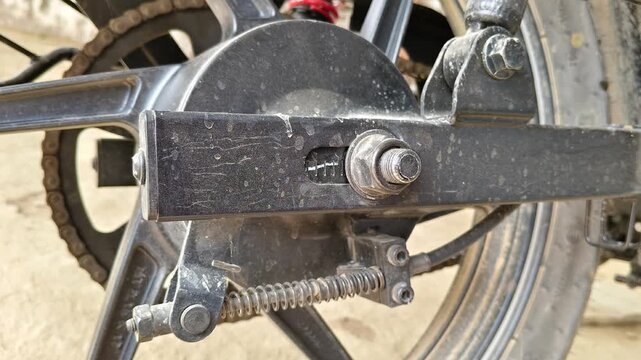 motorcycle rear wheel assembly showing the axle bolt, swingarm, and drum brake linkage