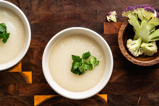 Cauliflower cream soup with grilled bread and cilantro on rustic wooden background
