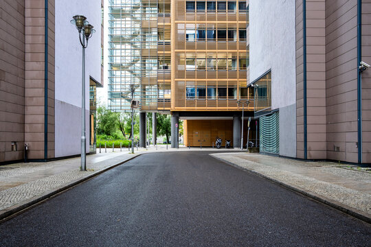 Quiet street alley of asphalt with lamppost between tall buildings and architecture guiding way route toward future destination in city