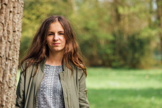 Portrait d'une jeune fille adolescente vers un tronc d'arbre dans un parc vert.