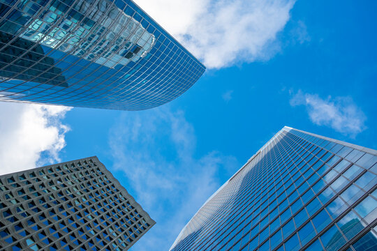 Modern glass skyscraper seen in perspective against sky shows architecture in urban La Defense Paris France with strong corporate lines and height