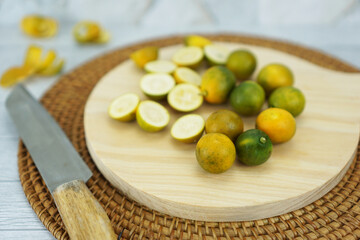 A pile of several kimkit or kimkiat or kingkit oranges in a small woven bamboo bowl resembling a lime with a sweet taste like honey and a flesh texture that is not watery, the orange peel can be eaten