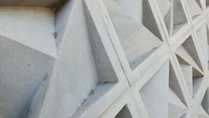 Grey concrete roster (original color, unpainted) as ventilation and decoration for a wall in a house with a 3D motif in the form of a large triangle and 2 small triangles