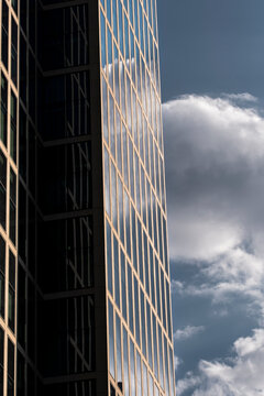 Modern urban office building facade with windows in architecture shadow against clouds showing a vertical dramatic exterior corporate design
