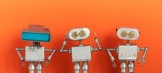 Futuristic technology concept. Three silver robots on peach color background. Close-up mechanical...