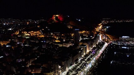 Obraz premium Nocturne aerial view of Alicante port, Postiguet Beach and the buildings next to the city center in the Mediterranean city of Alicante, Spain.