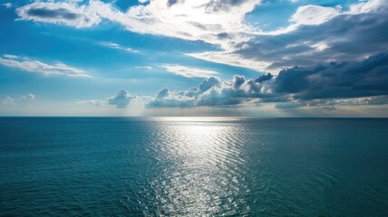 Obraz premium Serene ocean landscape with dramatic cloudy sky and sunlight reflection