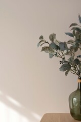 Minimal aesthetic home interior decor detail. Green vase with olive tree branch on wooden table, empty neutral beige plaster wall background with natural sunlight shadows. Sustainable interior design
