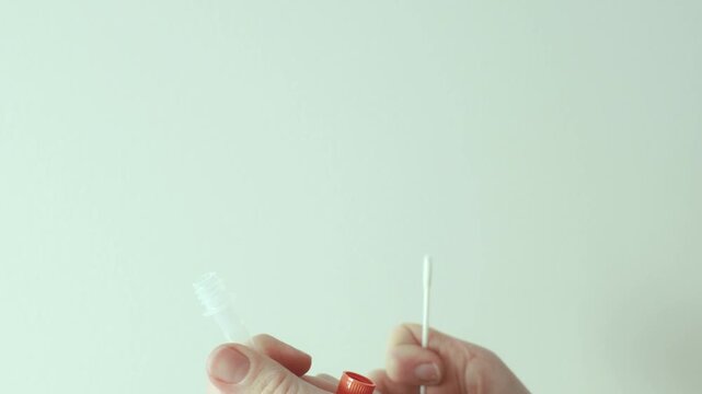 A woman performs a nasal swab for a rapid antigen self-test at home, inserting a swab into her nose to collect a sample. Concept of self testing, healthcare, and disease prevention.