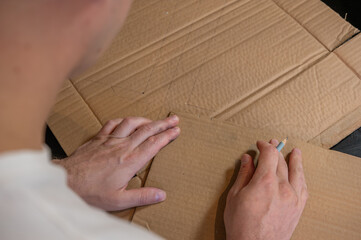 Close-up of hands working on a cardboard prototype at a desk. Startup project concept, product development, prototyping process, creativity, and innovation. Hands-on work, no face visible.