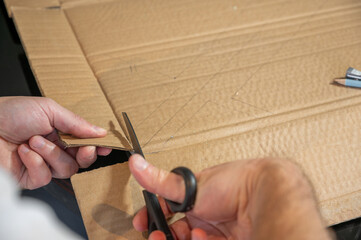 Close-up of hands working on a cardboard prototype at a desk. Startup project concept, product development, prototyping process, creativity, and innovation. Hands-on work, no face visible.