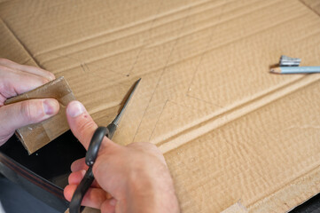 Close-up of hands working on a cardboard prototype at a desk. Startup project concept, product development, prototyping process, creativity, and innovation. Hands-on work, no face visible.
