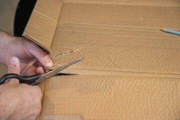 Close-up of hands working on a cardboard prototype at a desk. Startup project concept, product development, prototyping process, creativity, and innovation. Hands-on work, no face visible.