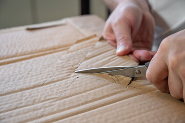 Close-up of hands working on a cardboard prototype at a desk. Startup project concept, product development, prototyping process, creativity, and innovation. Hands-on work, no face visible.
