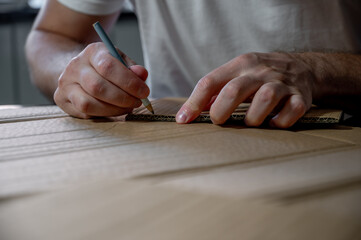 Close-up of hands working on a cardboard prototype at a desk. Startup project concept, product development, prototyping process, creativity, and innovation. Hands-on work, no face visible.