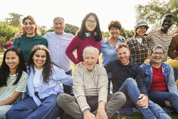 Fototapeta premium Group of multigenerational people smiling in front of camera - Multiracial friends of different ages having fun together - Main focus on center senior man face