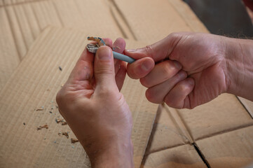 Close-up of hands sharpening a pencil with a sharpener on a desk. Concept of preparation, focus, creativity, learning, and project development. Manual work, no face visible.