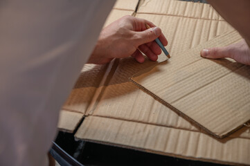 Close-up of hands working on a cardboard prototype at a desk. Startup project concept, product development, prototyping process, creativity, and innovation. Hands-on work, no face visible.