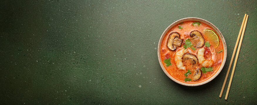 Tom yum soup with shrimp and mushrooms in bowl with chopsticks top view, traditional Thai soup