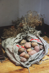 worek ziemniaków na podłodze, suszone polne kwiaty w tle © Katarzyna