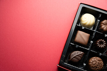 Assorted chocolate pralines in gift box on red background