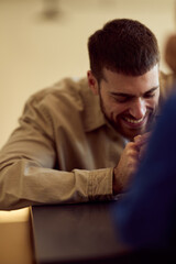 Obraz premium Smiling Man At Diner Table Leaning Forward With Hands clasped, Casual Friendly Moment