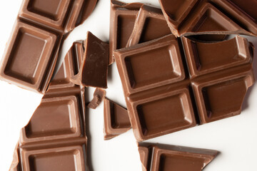 Chocolate bar broken into pieces on clean white surface