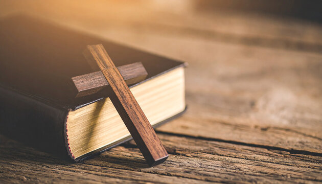 Handcrafted wooden cross on vintage Bible, wooden table, spirituality, Christian faith, cultural artifact.