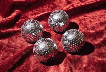 Four mirrored spheres rest on a draped, deep red velvet fabric