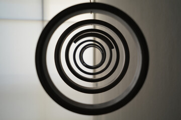 Black concentric circle sculpture, metallic rings on white wall, modern art installation, for website or presentation background, isolated on transparent background, png