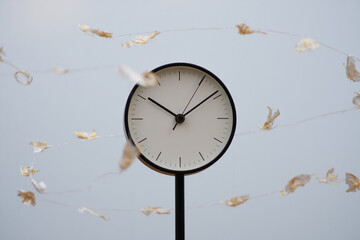 Clock with falling leaves, time passing concept, for website or presentation, overlay effect, isolated on blue background