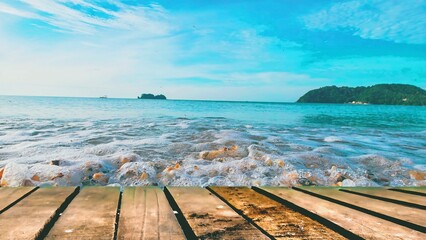 Ocean waves reaching wooden deck, tropical beach seascape background.