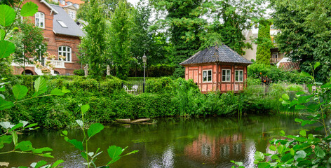 Obraz premium Picturesque Historic Timber Framed Pavilion on the Banks of the Odense River in Denmark Surrounded by Lush Gardens and Traditional Architecture