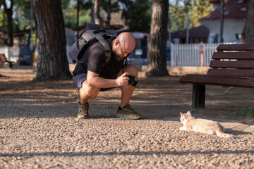 Man Taking Photos in a Public Park. Photographer Capturing Moments in Urban Park. Male Photographer Using Camera Outdoors in Park. Man with Camera Photographing Nature in Park.