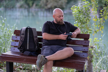 Photographer Checking Captured Images on Digital Camera. Photographer Reviewing Photos on Camera Screen. Photographer Checking Camera Screen Outdoors. Photographer Reviewing Shots After Shooting.